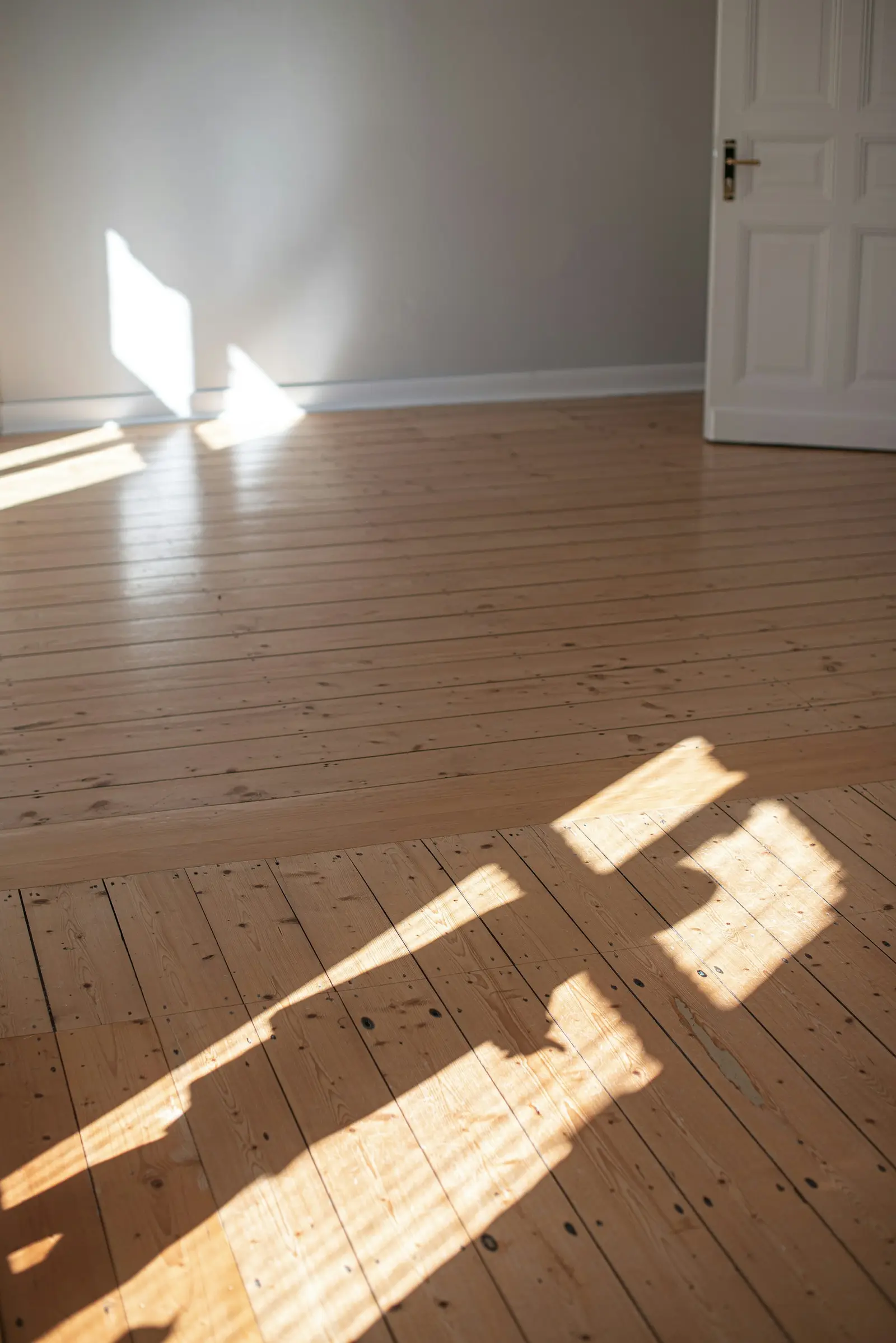 Helle Holzdielen mit Sonnenstreifen in einem leeren Raum